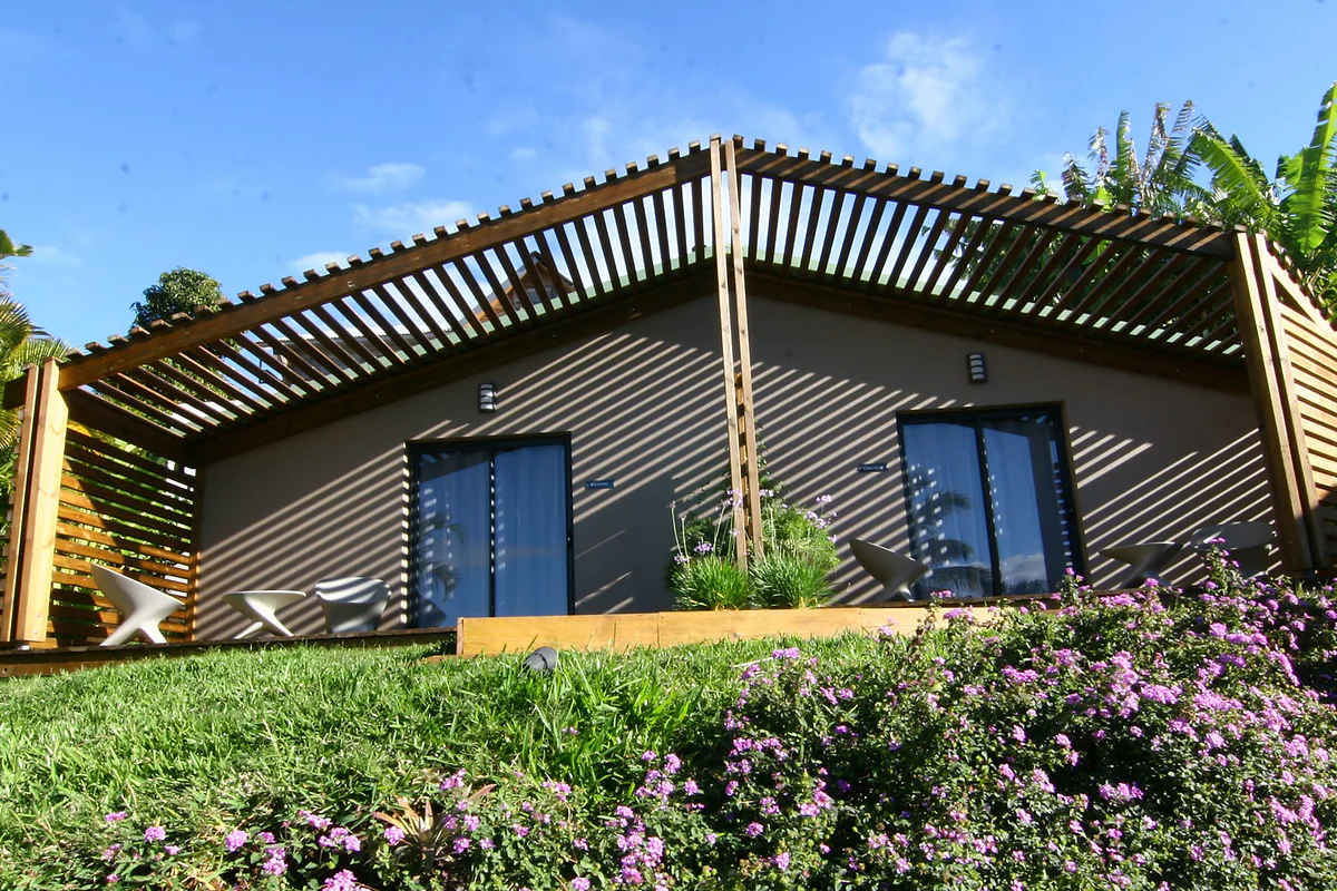 La chambre Camphre, une maisonnette en bois au milieu de la pelouse et des fleurs, sous le ciel bleu