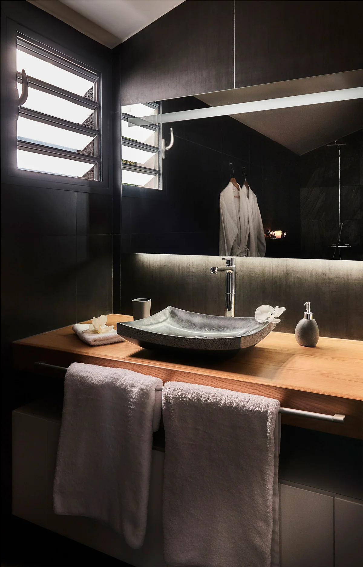 La salle de bain : une vasque en pierre sur un plan en bois et les serviettes