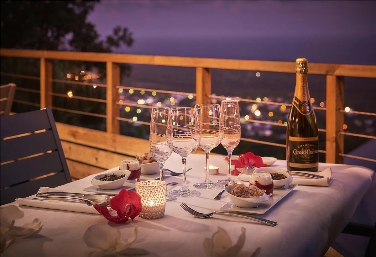 La table d'hôtes dressée sur la terrasse le soir, sous les guirlandes lumineuses