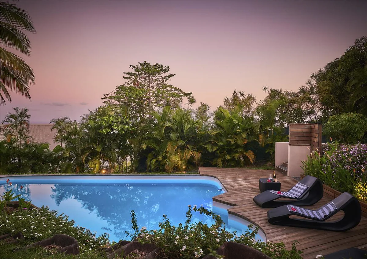 La piscine et le deck au coucher du soleil, avec l'océan au loin