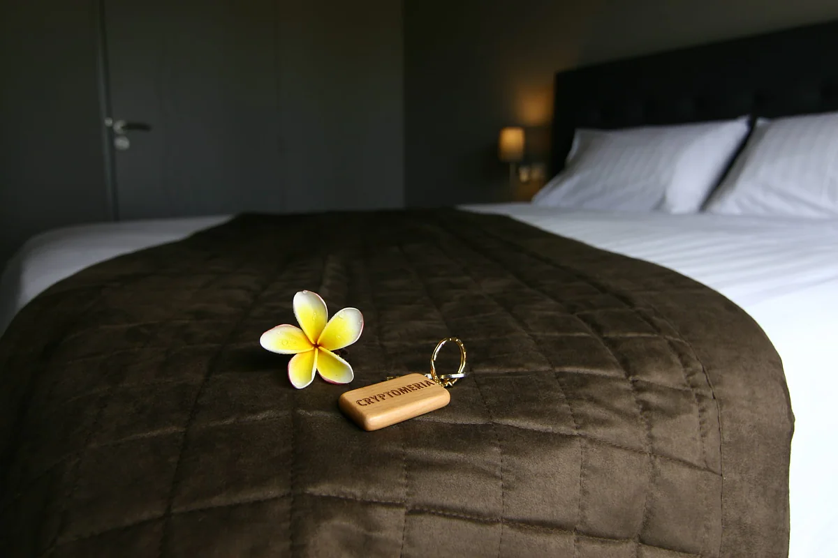 Une fleur de frangipanier et la clé sur le lit de la chambre Cryptoméria