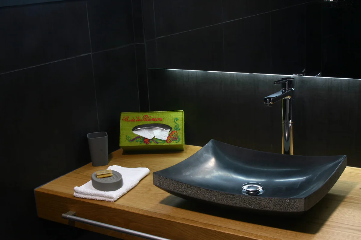La salle de bain : vasque en pierre, plan en bois et savons de l'île