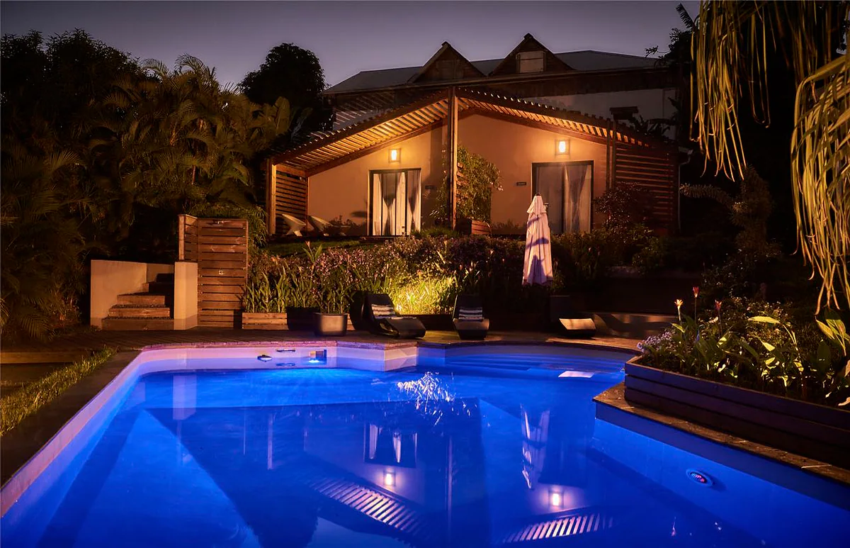 La maison illuminée le soir, au-dessus de la piscine bleue