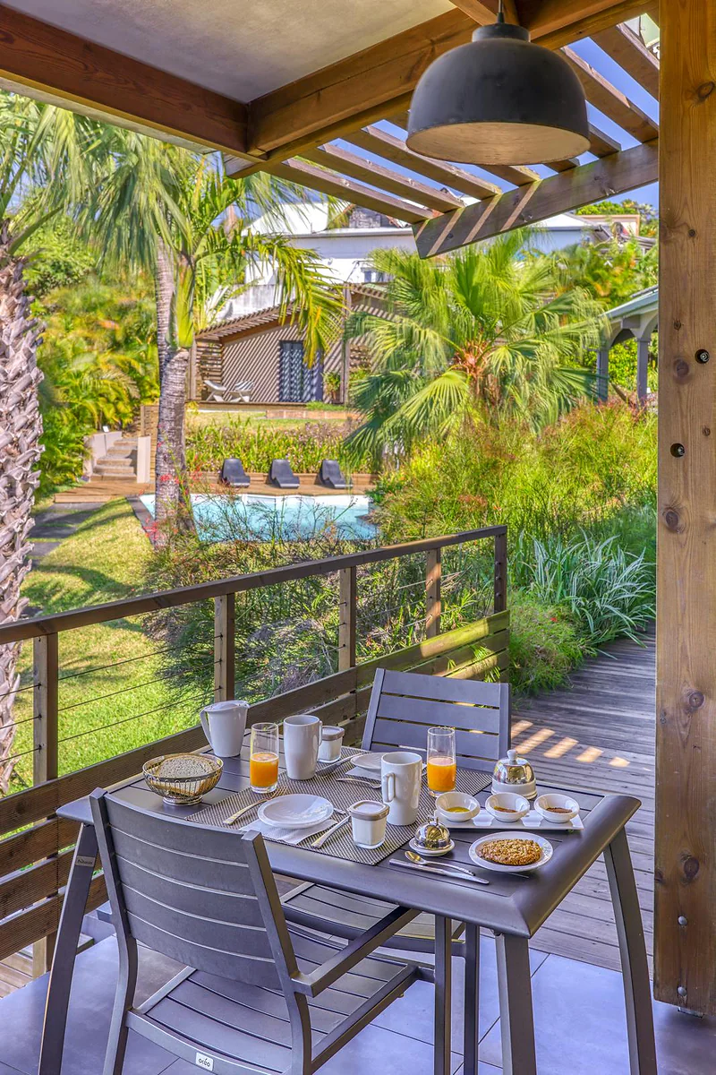 La table du petit déjeuner dressée sur la terrasse couverte, devant le jardin