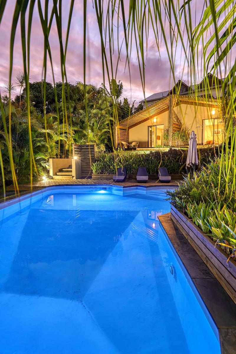 La piscine éclairée le soir, devant la maison illuminée