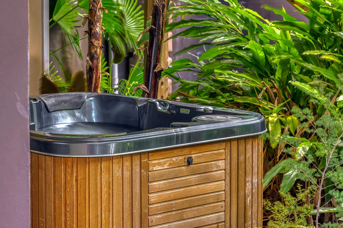 Le jacuzzi en bois entouré de plantes tropicales, en journée