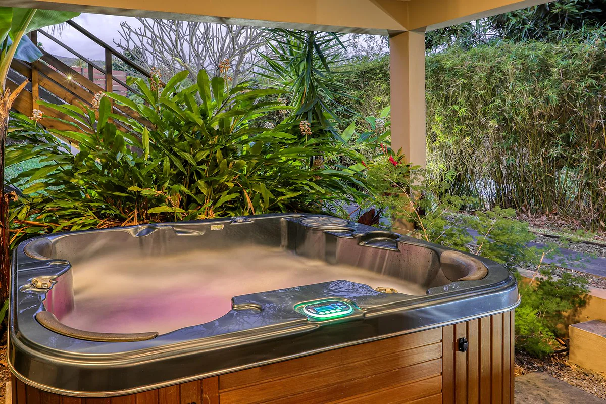 Le jacuzzi éclairé le soir, entouré de plantes tropicales