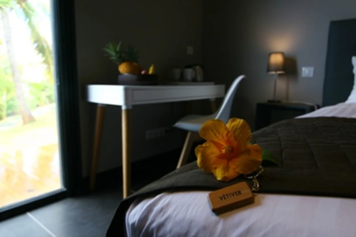 Une fleur d'hibiscus et la clé de la chambre Vétiver posées sur le lit