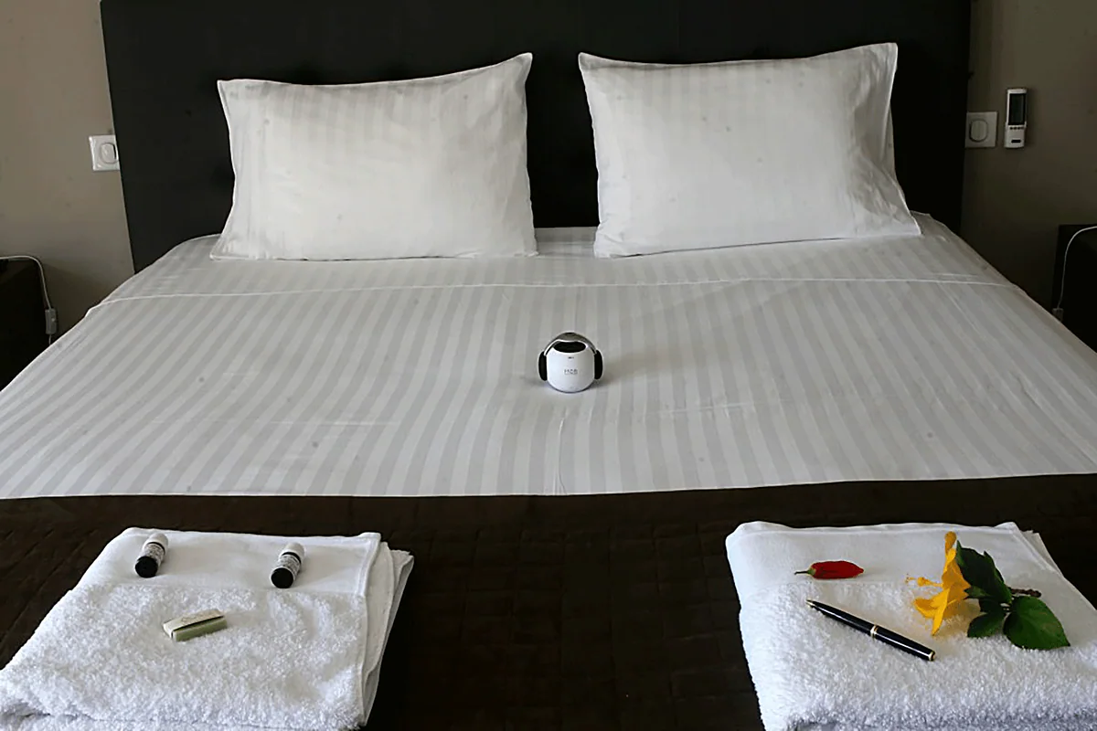 Le lit préparé : serviettes roulées, petits flacons d'huiles essentielles et une fleur